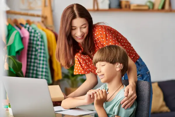 stock image A mother lovingly engages with her hearing impaired son while he studies.