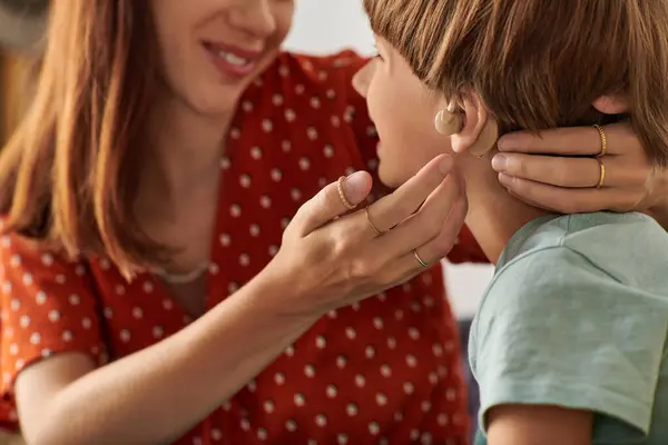 stock image A mother gently helps her hearing impaired son while they share a warm moment.