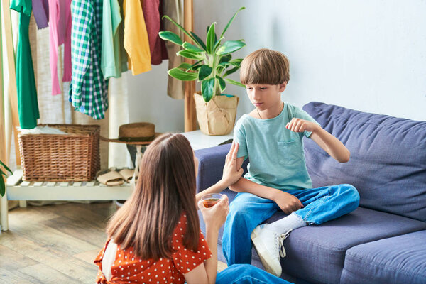 Mother engages playfully with her hearing impaired son in a cozy living room.