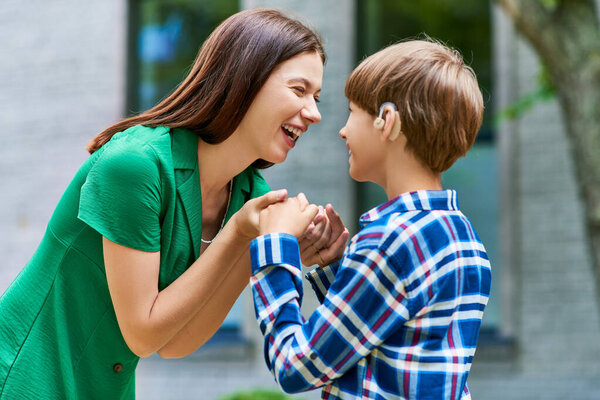 A mother shares laughter and love with her hearing impaired son in a joyful interaction.