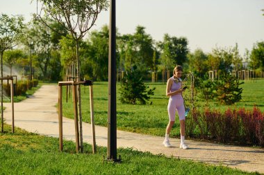 Genç bir kadın canlı bir parkta geziniyor, temiz havanın tadını çıkarıyor..