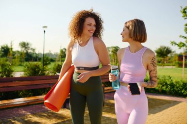 Parktaki güneşli bir günde iki kadın spor ve kahkaha üzerine bağ kurar..