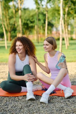 Sevgi dolu bir çift yoga minderlerinde rahatlar, neşeli bir parkta kahkahalarını paylaşır..