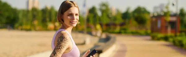 stock image A young woman strolls through a vibrant park, radiating happiness.