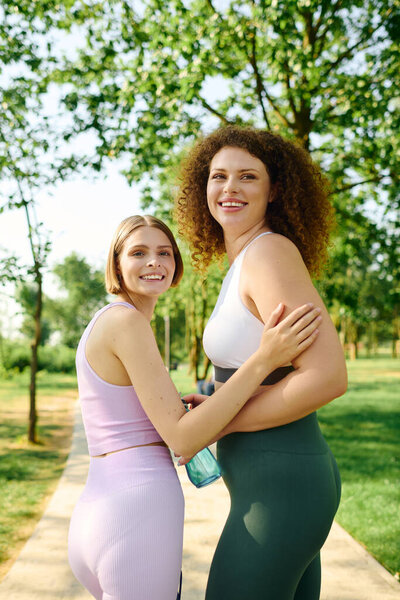 Две счастливые женщины обнимаются во время пребывания в пышном зеленом парке.