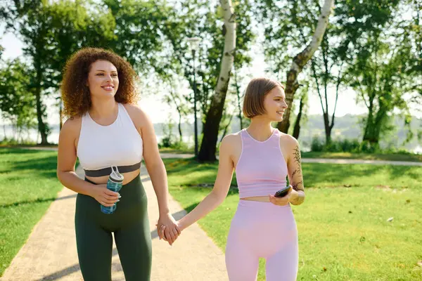 stock image A joyful couple walks hand in hand through a vibrant park on a sunny day.