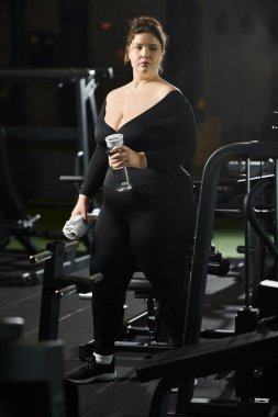 Genç bir kadın spor salonunda vücut pozitifliğini kucaklayarak spor yapıyor..