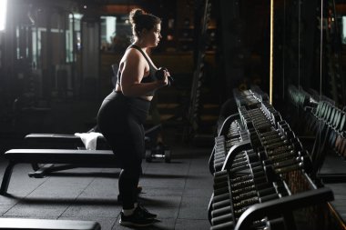 Genç bir kadın spor salonunun atmosferinde vücut pozitifliğini kutluyor..