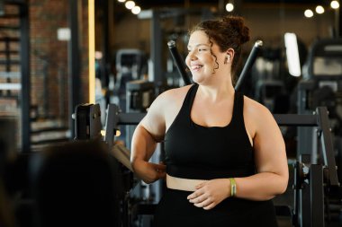 Kendine güvenen genç bir kadın spor salonundaki etkin kıyafetinin tadını çıkartıyor..