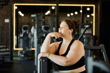 Büyük beden bir kadın spor salonundaki antrenman sırasında gücünü ve pozitifliğini kucaklar..