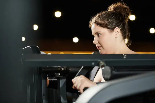 stock image A plus-size woman focuses on her workout, promoting body positivity in a vibrant gym atmosphere.