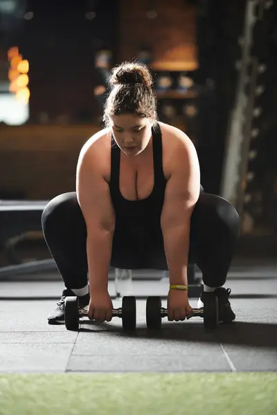 stock image A plus-size woman confidently lifts dumbbells in activewear, showcasing strength and determination.