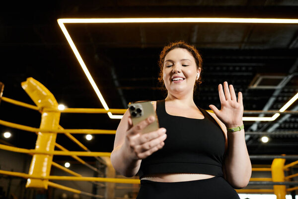 Женщина plus-size наслаждается рутиной тренировок, с удовольствием общаясь по телефону в тренажерном зале.