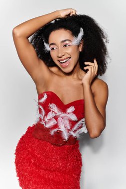 A joyful young woman showcases her stylish red ensemble with feather details and curly hair, exuding confidence. clipart