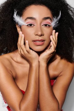 Genç bir kadın göz kamaştırıcı kırmızı elbisesini tüy detaylarıyla sergiliyor, kendine güven ve tarz yayıyor..