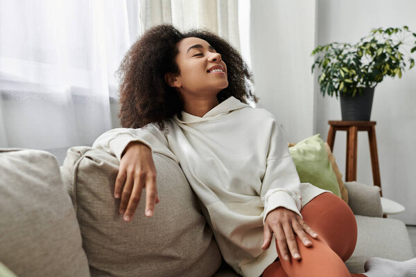 Молодая женщина наслаждается спокойным моментом дома, обнимая комфорт в своем уютном одеянии.