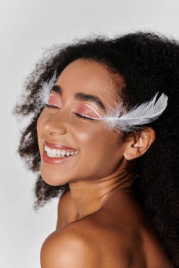 A young woman with curly hair radiates joy in a bold red ensemble, adorned with feathers, against a soft grey backdrop. clipart