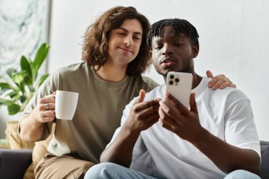 İki ortak, akıllı telefondan içeriği incelerken evde kahkaha ve bağlantı paylaşıyor.