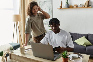 A couple share a joyful moment at home, engaging in work and conversation by their desk. clipart