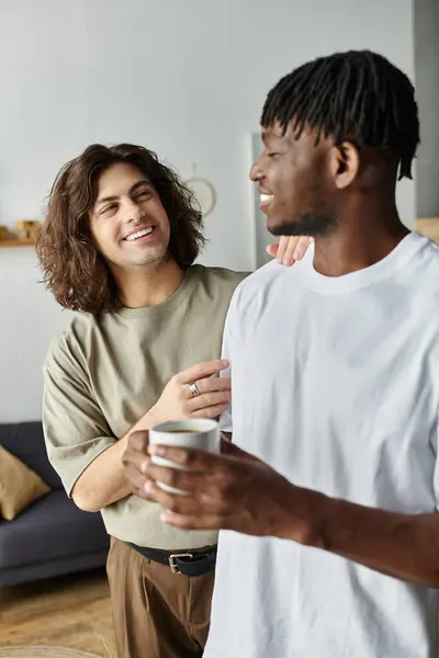 stock image Two partners share smiles and warmth while holding mugs in a comfortable living space.