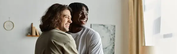 Stock image Two joyful men share a heartfelt embrace, smiling warmly in their inviting living space.