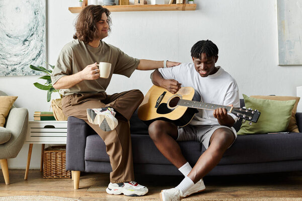 Счастливая пара разделяет нежный момент, в то время как один играет на гитаре, а другой пьет кофе..