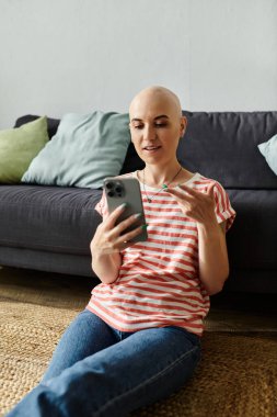 Alopecia hastası genç bir kadın rahat bir ortamda telefonla konuşurken gülümsüyor..