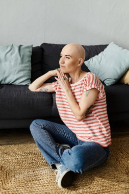 Alopecia hastası genç bir kadın yerde sakince oturur, rahat mekanını yansıtır..