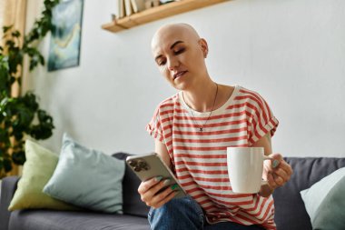 Kel bir kadın şık bir ortamda bir bardakla rahatlarken telefonuyla meşgul oluyor..