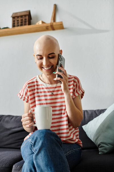 Веселая женщина улыбается и потягивает свой напиток, болтая по телефону, излучая позитив..