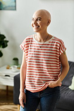 Çekici, genç ve kel bir kadın kendine güvenerek ayakta duruyor, şık çizgili elbisesiyle neşe saçıyor..