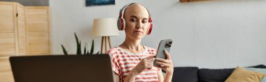 Güzel, kel bir kadın telefonundan müzik dinliyor, rahat bir atmosfere dalmış..