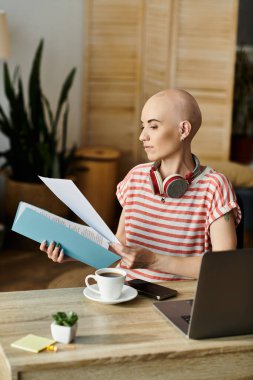 Güzel, kel bir kadın, sakin ve şık bir çalışma alanında kahvesini yudumlarken belgelere bakıyor..