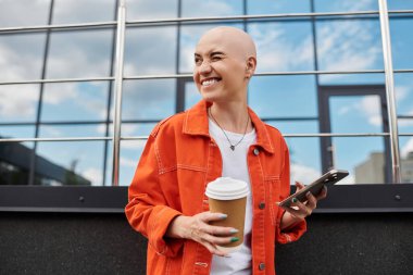 Genç kel bir kadın güneşli bir günün tadını çıkarıyor. Kahvesini yudumluyor, telefonuna mesaj atıyor, neşe saçıyor..