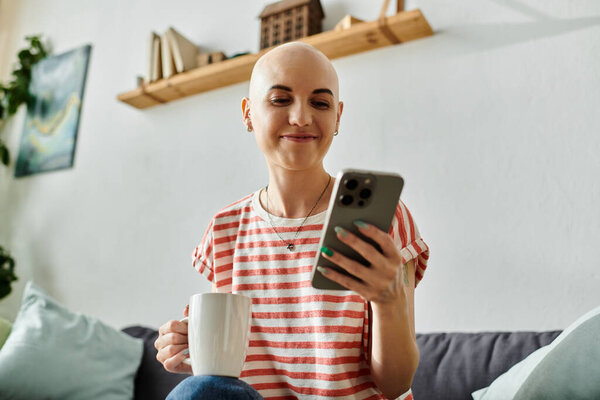 Веселая лысая женщина наслаждается кофе во время помолвки со своим смартфоном, источая тепло.