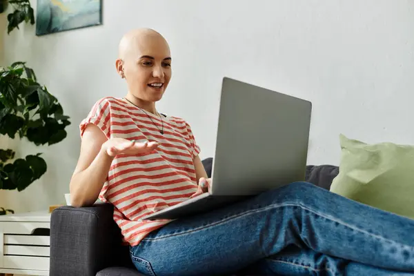 stock image A cheerful bald woman chats animatedly on her laptop, capturing the joy of connection.