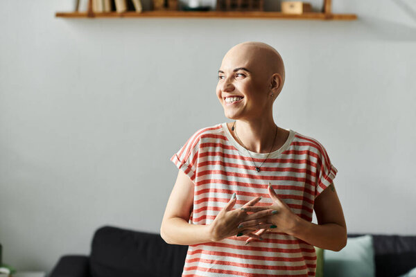Лысая молодая женщина излучает счастье, стоя в своем уютном доме.