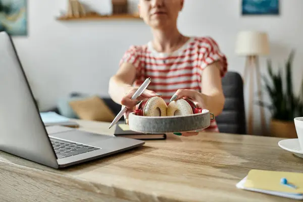 Stock image A vibrant woman shares freshly baked bagels while seated at a wooden table.