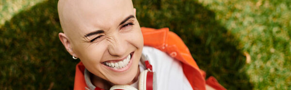 Веселая лысая женщина с алопецией светится от радости, впитывая солнце в парке..