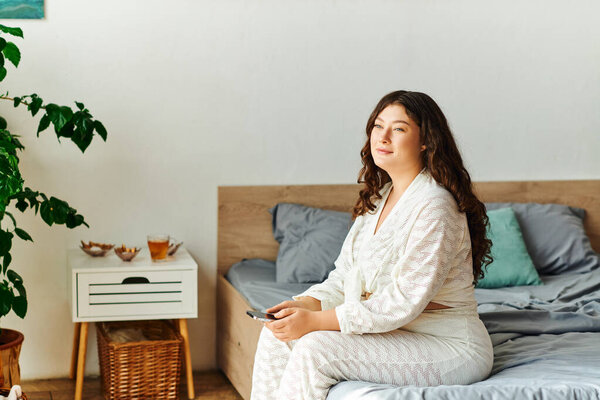 A young plus size woman enjoys a peaceful moment at home, reflecting while seated on her bed.