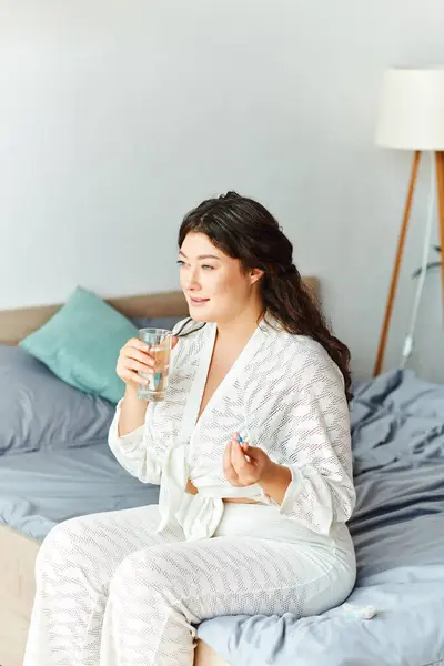 stock image Sipping a cool drink, a young plus size woman relaxes comfortably in her stylish bedroom.