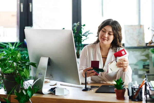 stock image The woman is seated at her desk, engaged in crafting with colorful boxes and vibrant decor.