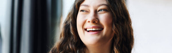 A cheerful young plus size woman enjoys a moment of happiness at office, radiating positivity.
