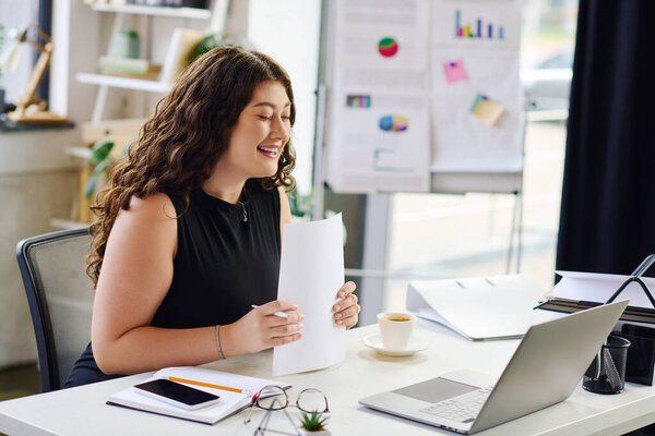 Живой молодой профессионал занимается своей работой, принося позитив в офис при просмотре важных документов..