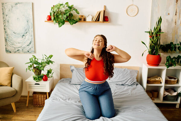 A young plus size woman smiles as she stretches playfully on her bed, surrounded by lovely plants and sunshine.
