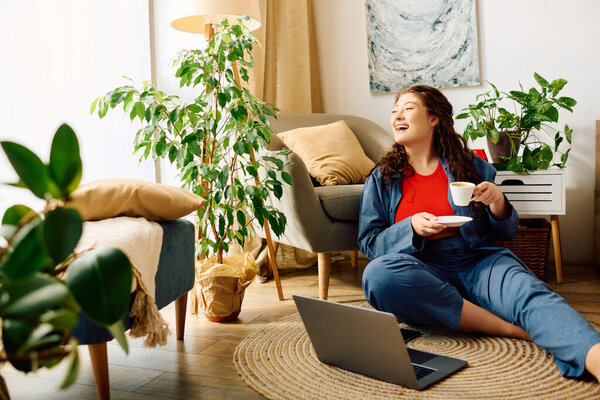 Веселая молодая женщина с вьющимися волосами расслабляется дома, потягивая чай в окружении зелени и комфорта.