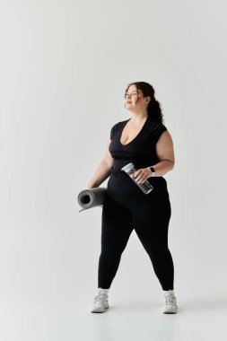 Kendine güvenen, kilolu bir kadın yoga minderi ve kilolarıyla hazır bekliyor..