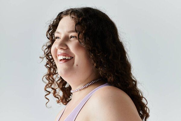 A joyful plus size woman exudes confidence and elegance while smiling beautifully in soft light.