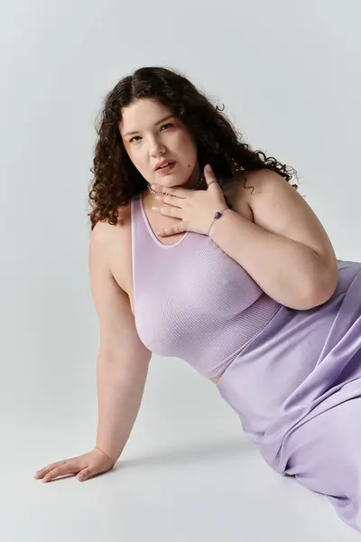 stock image A stunning plus size woman showcases her beauty while lounging casually in soft lavender.