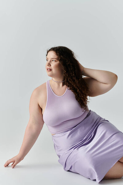 Потрясающий плюс размер женщина откидывается элегантно в лавандовый наряд, излучая уверенность и изящество.